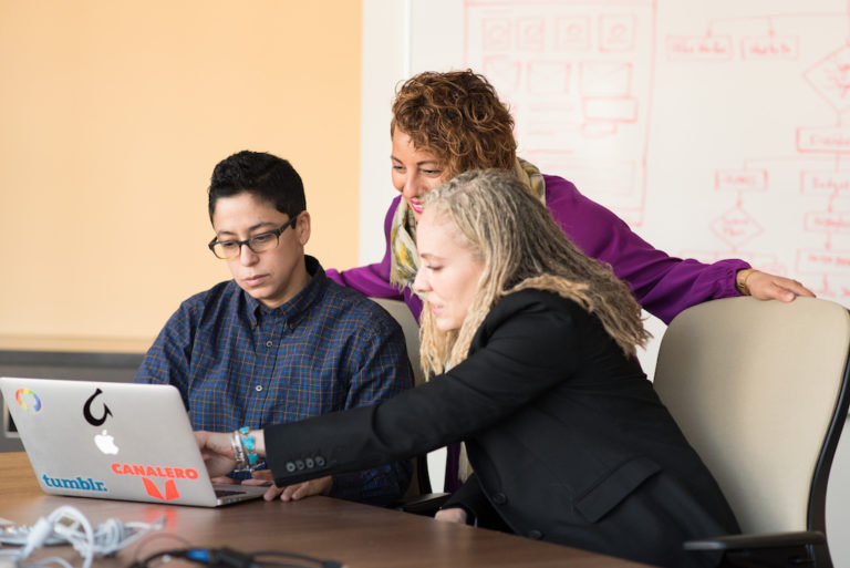 Three software engineers looking at a laptop