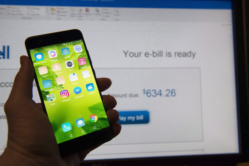 A cell phone is held up in front of video screen in this photo illustration