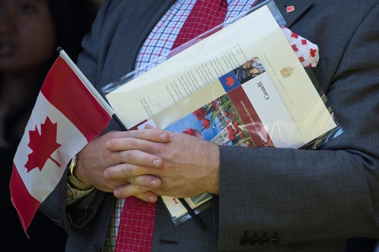 A new Canadian holds a Canadian flag, their citizenship certificate and a letter signed by Prime Minister Justin Trudeau at a Canada Day citizenship ceremony in West Vancouver in July 2019.