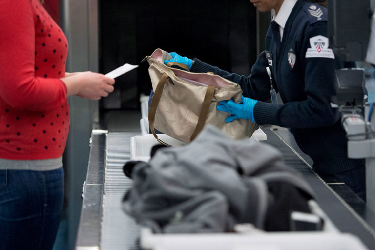 A Canadian Air Transport Security Authority official performs security checks of passengers and their carry-ons at Vancouver International Airport in February 2017