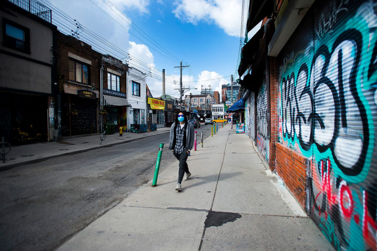 A lone person walks past closed businesses in Kensington Market in Toronto in April 2020.