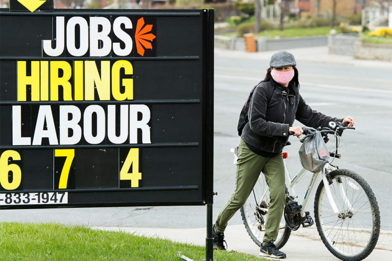 A woman looks at a jobs sign in Toronto in April 2020. The Canadian Press/Nathan Denette