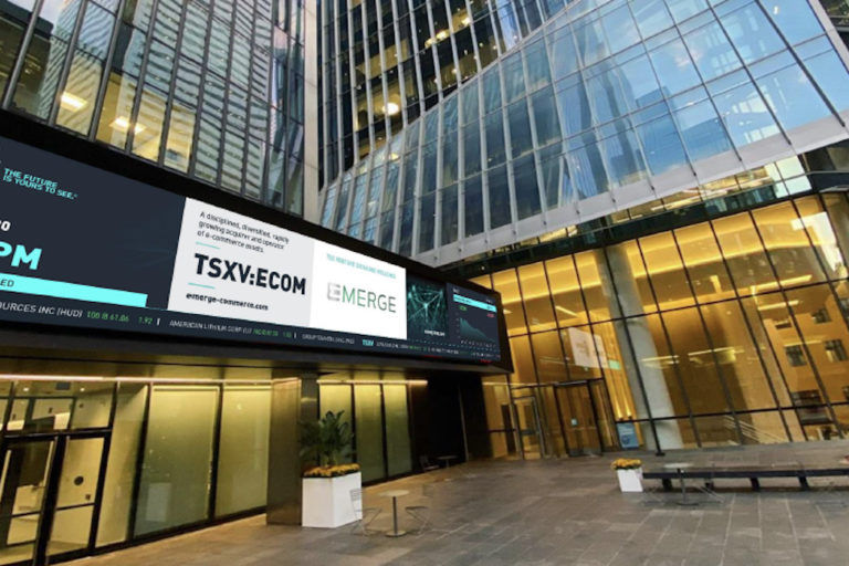 A screen displays a TSXV and Emerge banner in front of several skyscrapers in Toronto’s downtown financial district.