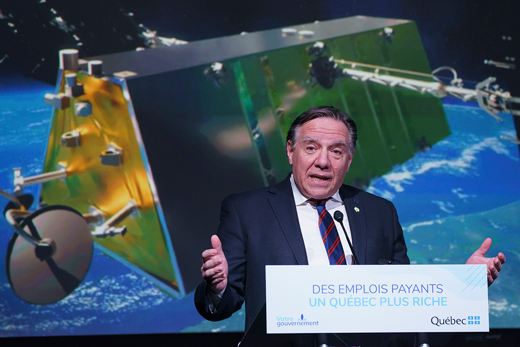 Quebec premier François Legault standing in front of a rendering of a Telesat low-Earth orbit satellite to announce funding for Telesat and MDA, in Montreal in February 2021.