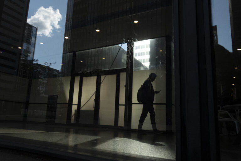 A man walks though a downtown Toronto office building with other buildings reflected in a window in this June 11, 2019 photo. The future of Canada's social safety net is pending after the federal budget made no mention of employment insurance reform, despite the Liberals having promised to modernize the program. THE CANADIAN PRESS/Graeme Roy