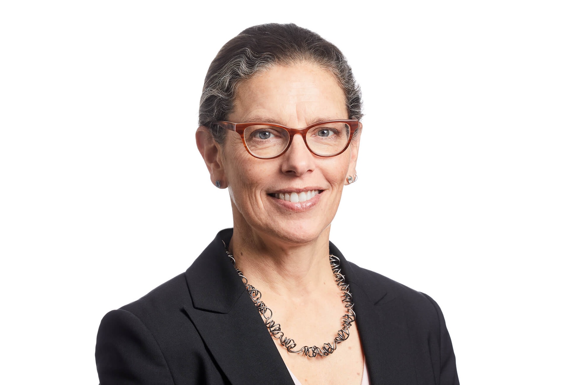 Tracey Black, CEO of Payments Canada is pictured in a headshot. She has tied back grey hair and wears tortoise shell glasses, and a black blazer.
