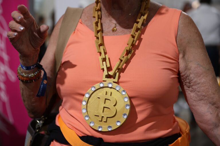 A Bitcoin 2021 Convention attendee wears an orange top and a gold-coloured Bitcoin chain necklace.