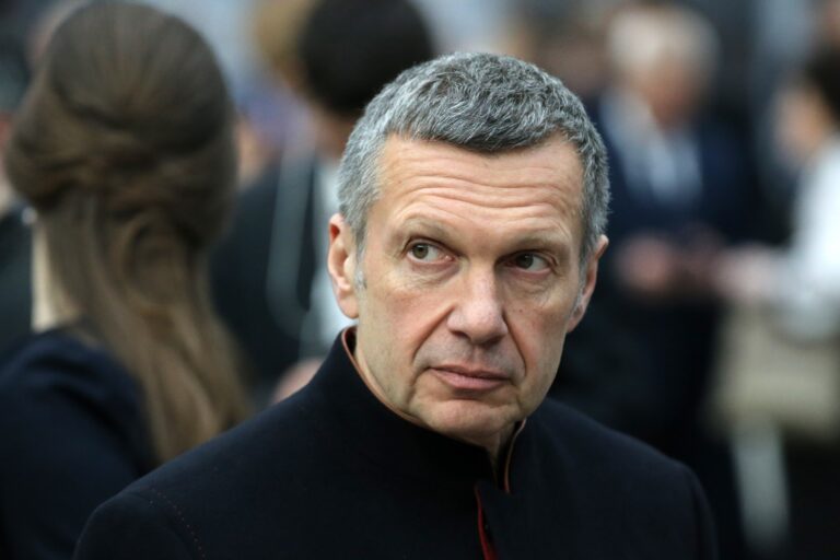 Russian television presenter Vladimir Solovyov is looking on the right side out of the corner of his eyes. The crowd in the background is blurred out.