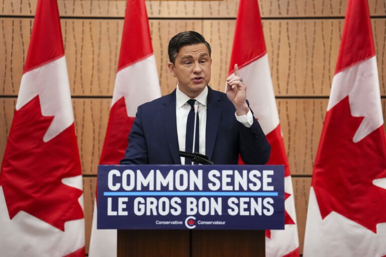 Conservative leader Pierre Poilievre speaking at a podium with a sign that says, “Common sense.” There are four Canadian flags in the background.