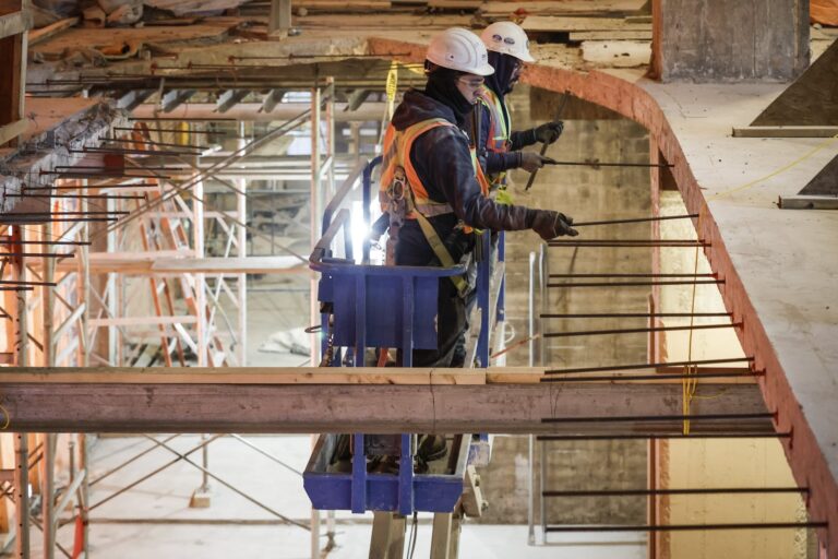 Construction workers toiling inside a building with scaffoldings around.