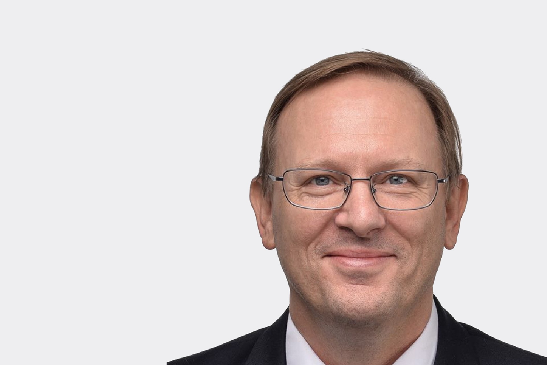 A headshot of Klaus Pflugbeil smiling. He is wearing a suit and spectacles.