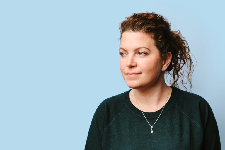 Loblaw Digital head Lauren Steinberg looking sideways. She is wearing a dark green sweatshirt with a silver pendant.