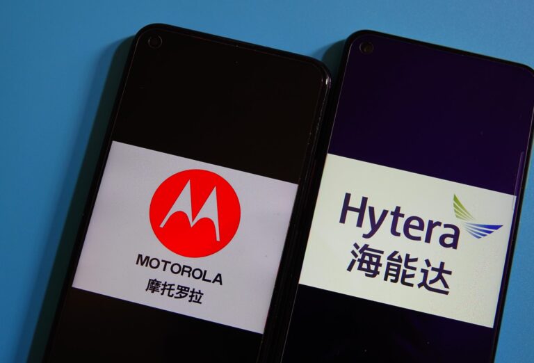 Two phones lay side by side on a blue background. The left shows a Motorola logo, and the right shows a Hytera logo.