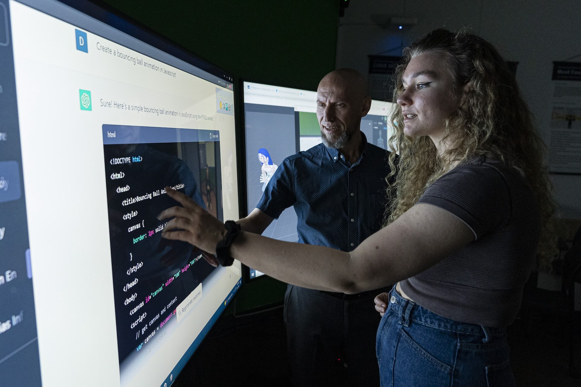 Two people pointing at a screen displaying a chat between an individual and ChatGPT, the AI-powered chatbot, presenting a code in a black window.