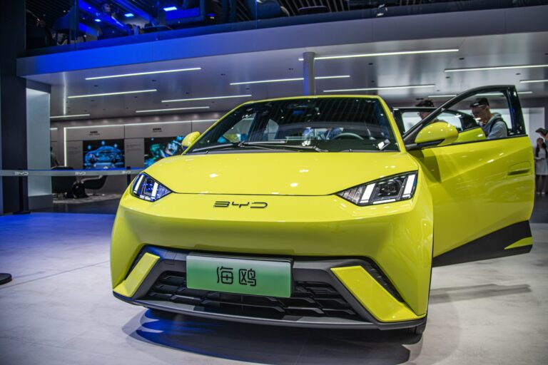 A fluorescent yellow BYD Seagull car with doors open at a showroom.