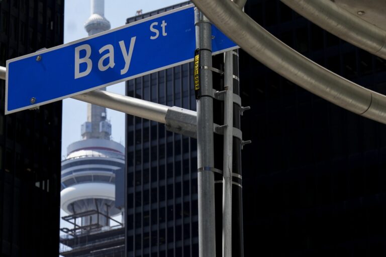 A blue street sign reads “Bay St.” The CN Tower is visible between buildings in the background.