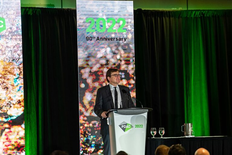 Natural Resources Minister Jonathan Wilkinson speaking at a podium with a screen behind him that reads, “2022, 90th anniversary.”