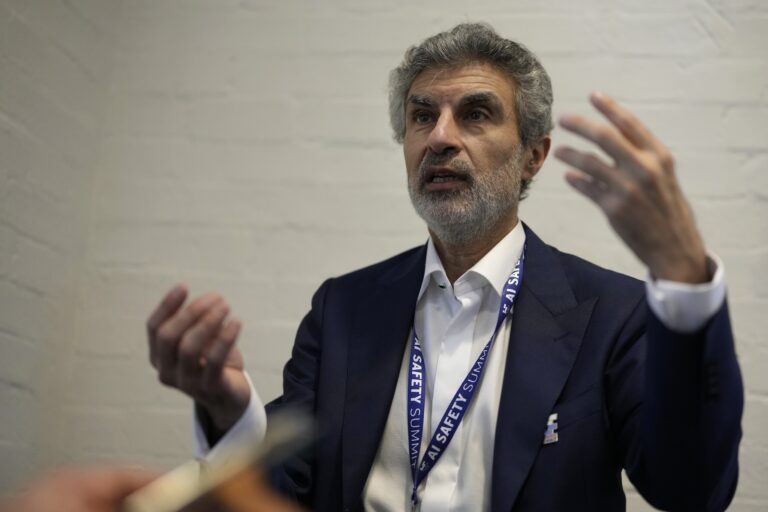 Université de Montréal professor Yoshua Bengio gesturing with both hands while talking. He’s wearing a lanyard around his neck that says, “AI Safety Summit.”