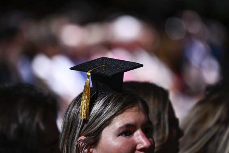 A person wearing a headband featuring a miniature mortarboard cap.
