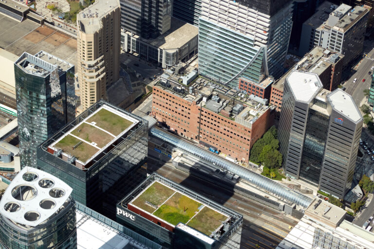 An aerial view of a rectangular, red-brick-sided building in downtown Toronto with clusters of cooling equipment on its roof.