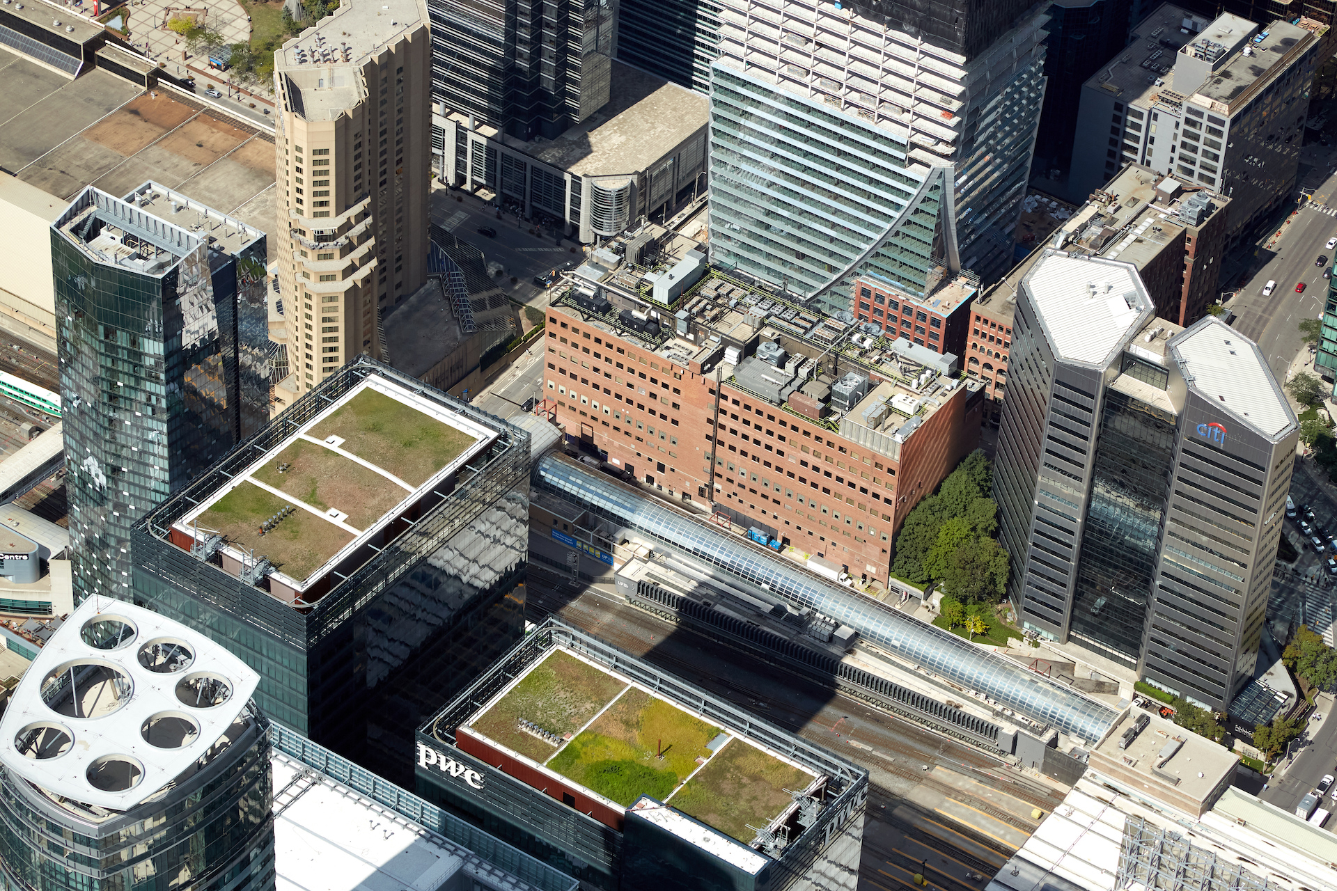 An aerial view of a rectangular, red-brick-sided building in downtown Toronto with clusters of cooling equipment on its roof.