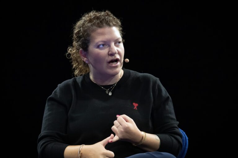 Lauren Steinberg, Loblaw’s senior vice-president of media, loyalty and digital wearing a microphone headset, speaking while gesturing with her hands. She is wearing a black sweater.