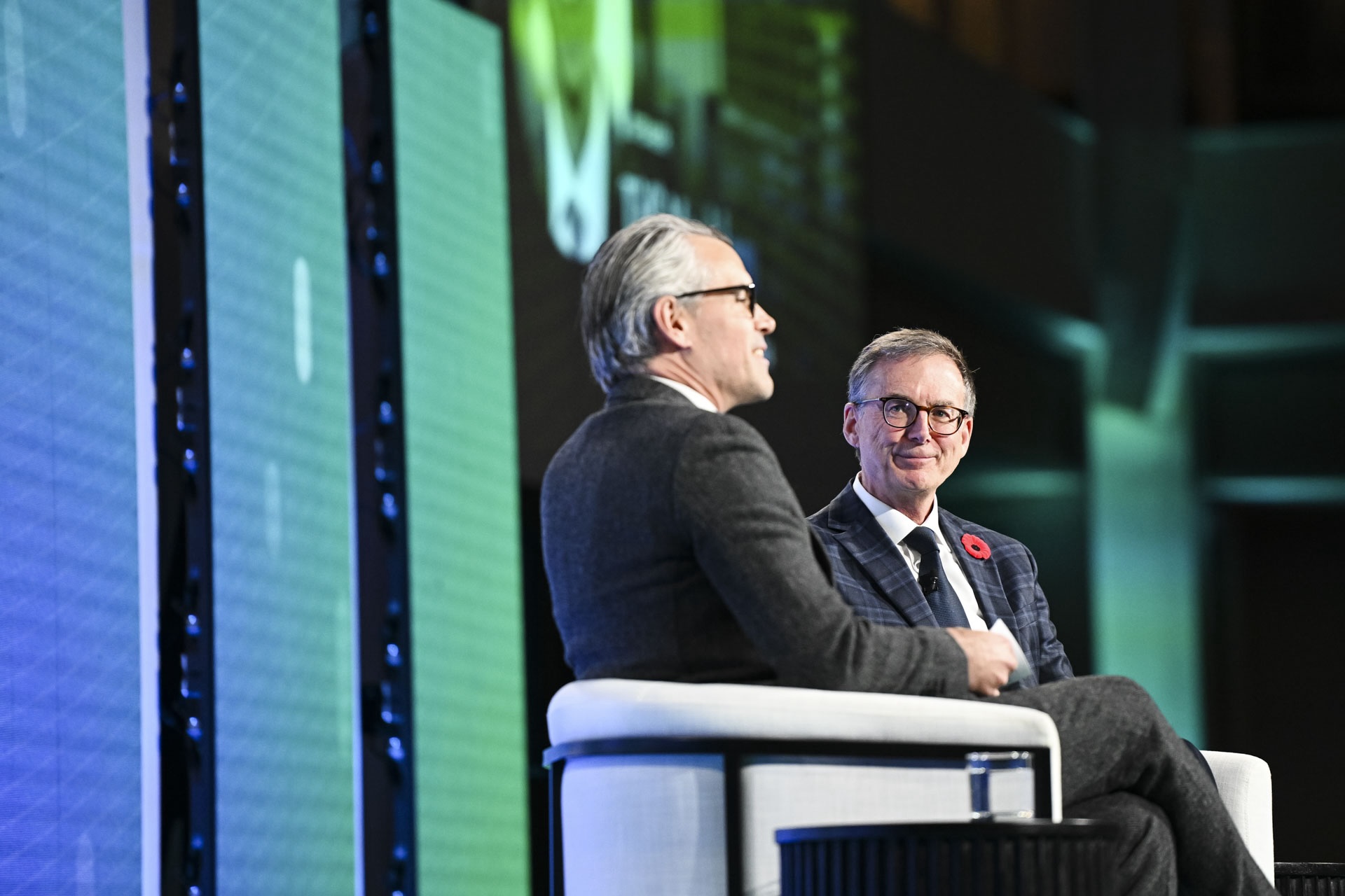 Bank of Canada governor Tiff Macklem and economics columnist Kevin Carmichael sitting on stage in suits, engaged in conversation against a backdrop with green and blue Logic logo.
