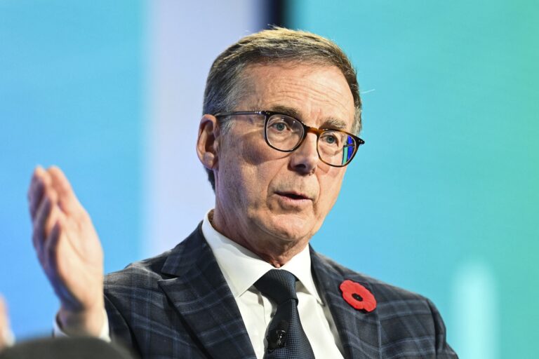 Bank of Canada Governor Tiff Macklem in a suit, speaking and gesturing with his right hand.