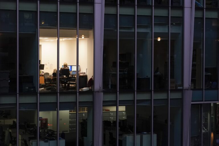 An employee works alone in a glass office building.