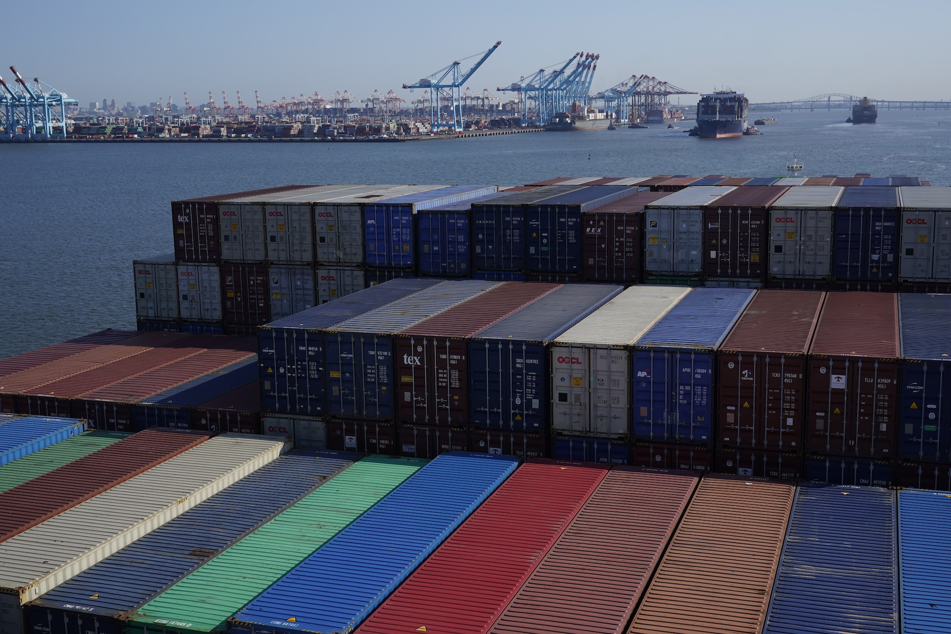 Multicoloured cargo containers are seen at the Port of New York and New Jersey, with numerous cranes and the estuary seen in the background.