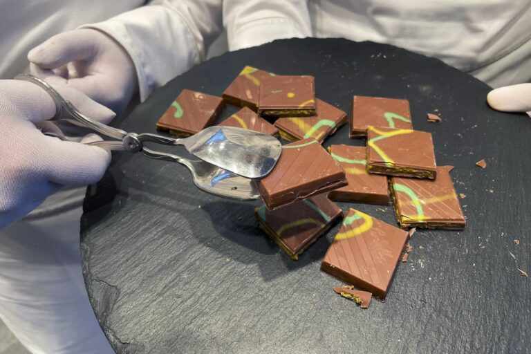 Silver prongs hold up a pile of Lindt chocolate atop a black table.