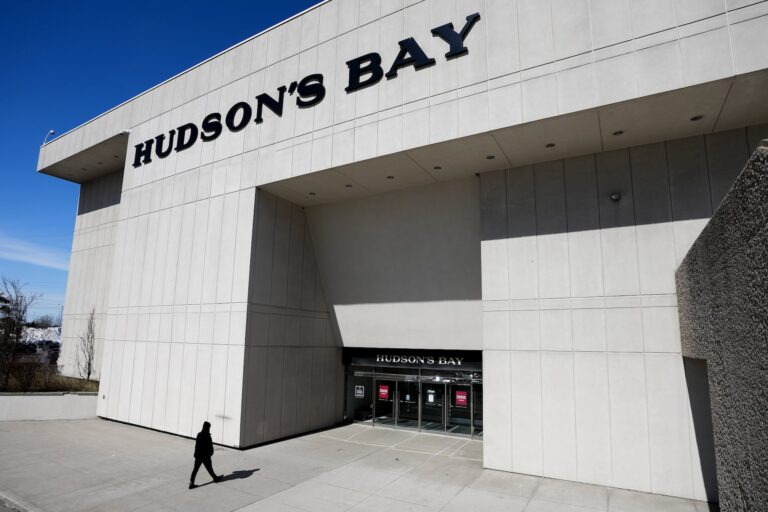 The outside of a large concrete Hudson's Bay store in Toronto. A person is walking towards the entrance.