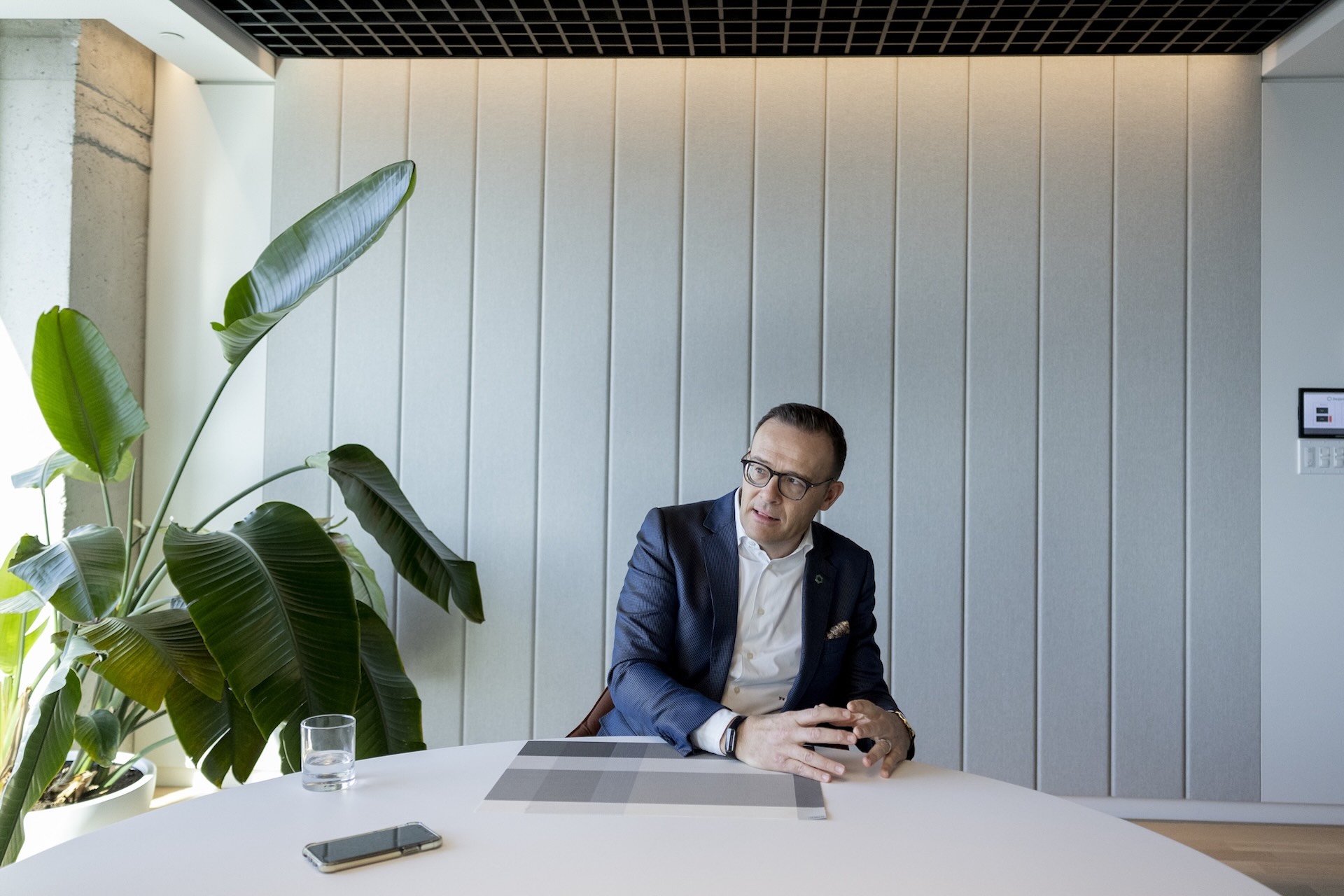 Guy Cormier, CEO and president of Desjardins, gestures with his hands while seated at a table with a plant to his left.