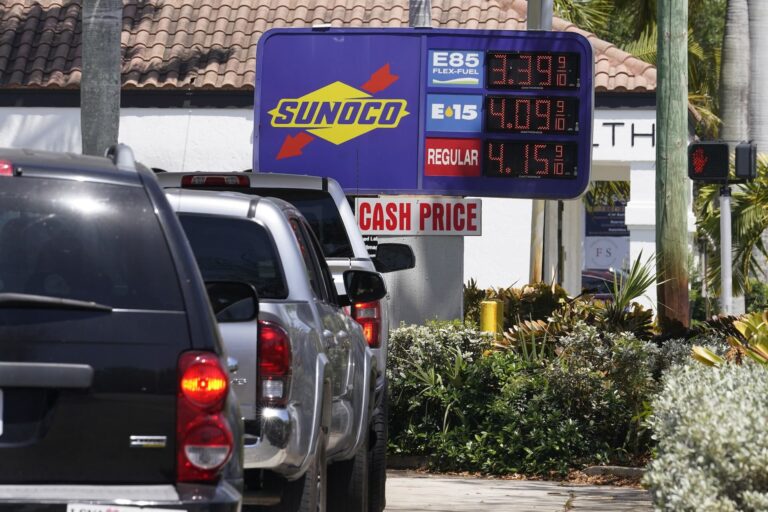A shot of vehicles queueing at a Sunoco station in Florida; the prices of fuels are displayed on an electronic sign.