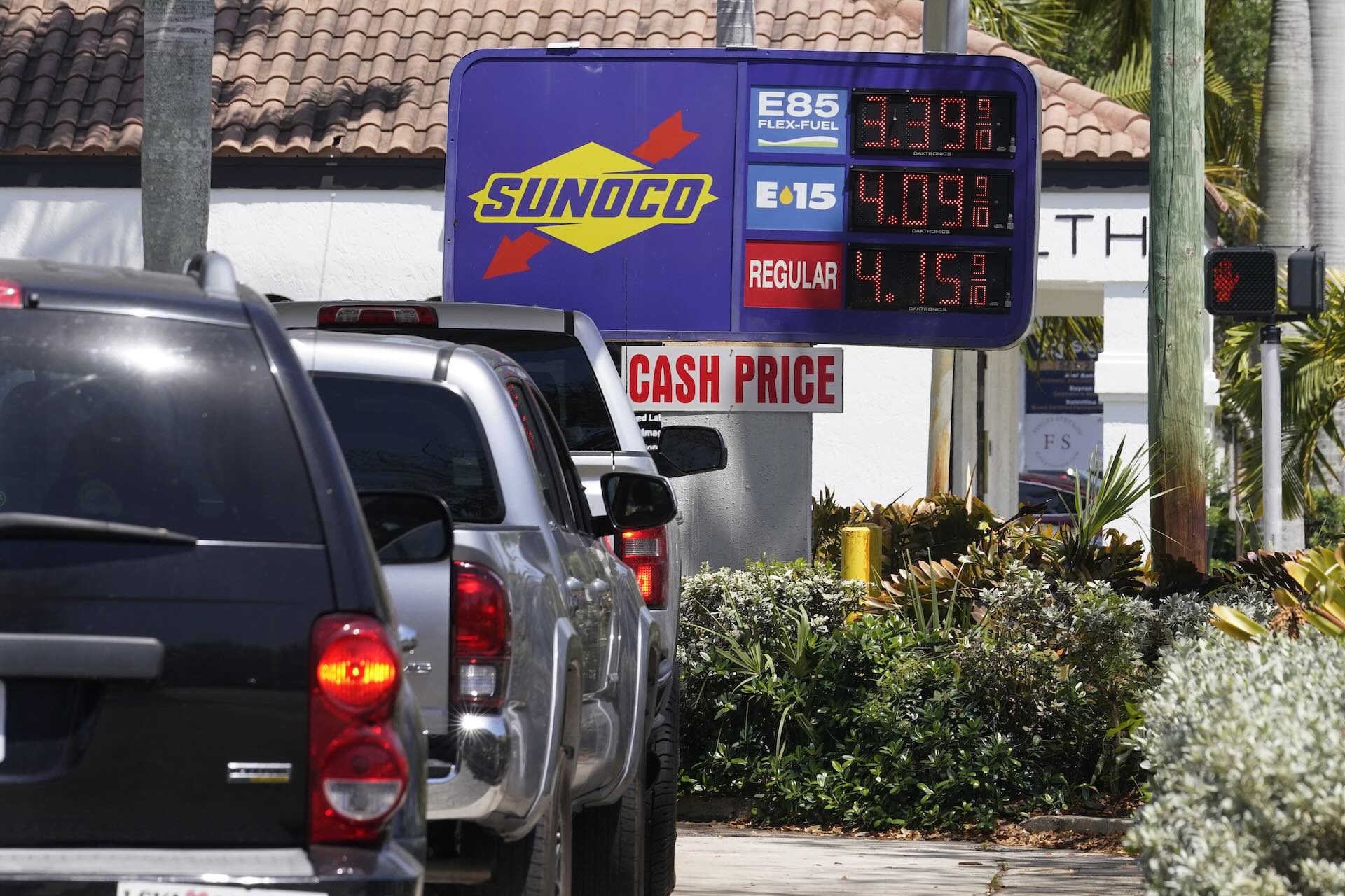 A shot of vehicles queueing at a Sunoco station in Florida; the prices of fuels are displayed on an electronic sign.