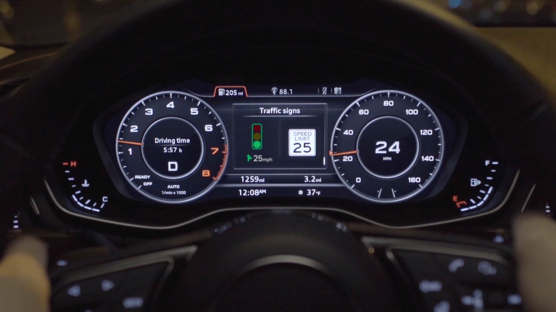A close-up of a dashboard display shot through a steering wheel. The display shows a speed limit sign reading "25" and an image of a green traffic light.