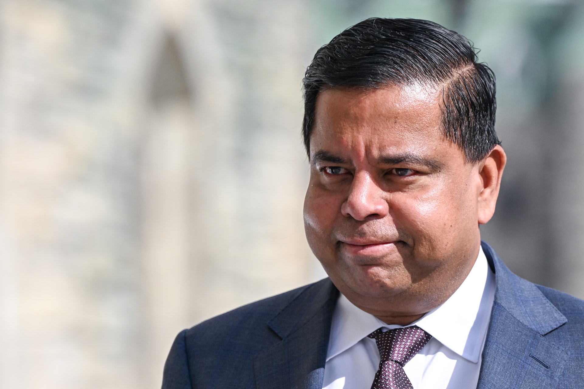 A closeup of Gary Anandasangaree in jacket and tie.