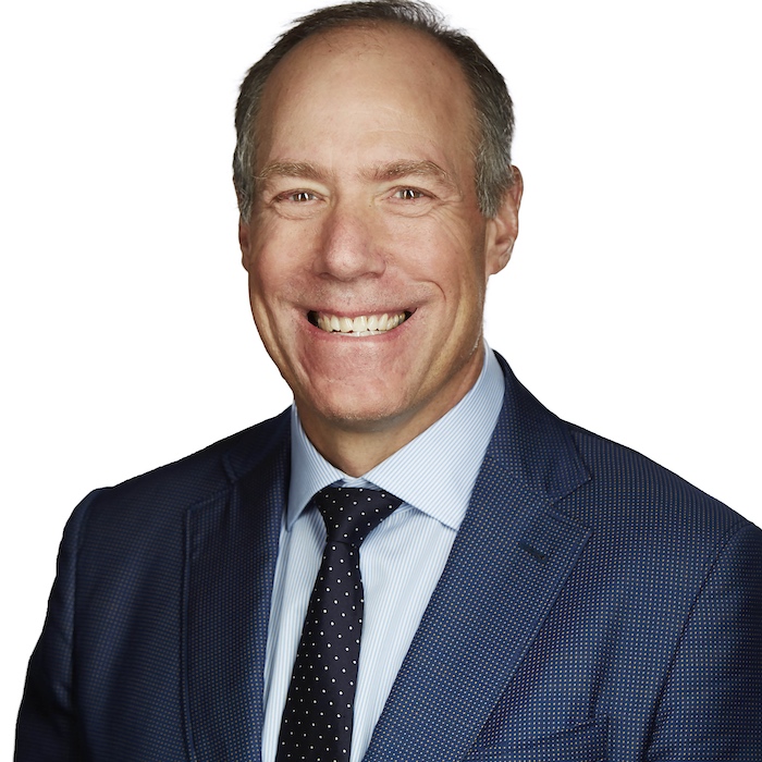 A head-and-shoulder portrait of Jim Jarrell. He's wearing a blue suit and tie and is smiling.