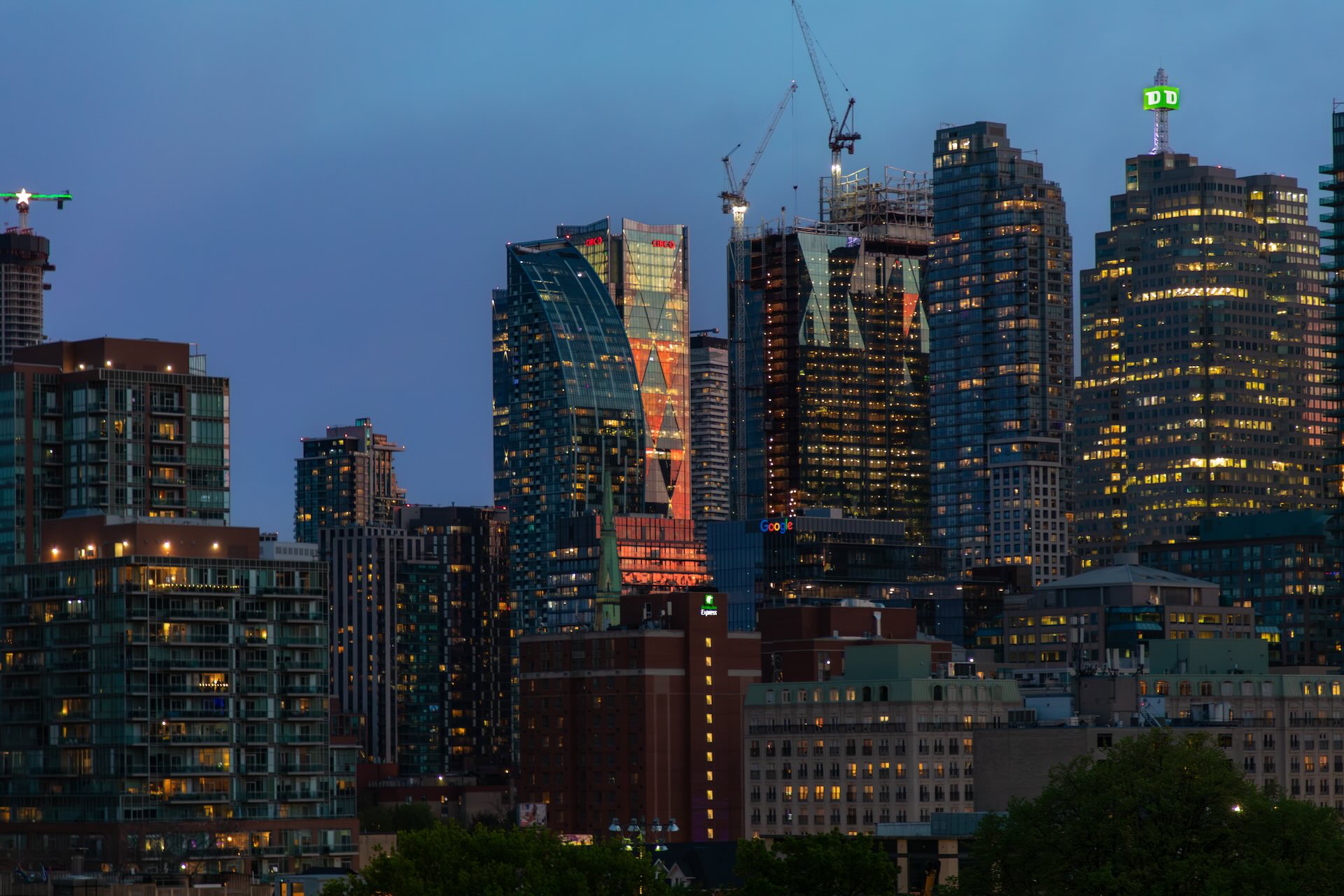 Image of the Toronto skyline with construction cranes rising above some buildings.