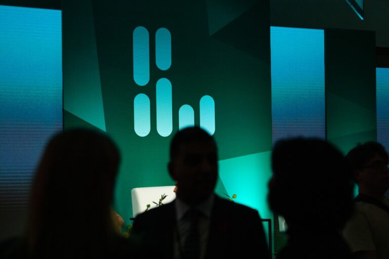 The Logic Summit logo onstage, lit in blue. Silhouettes of people can be seen in the foreground.