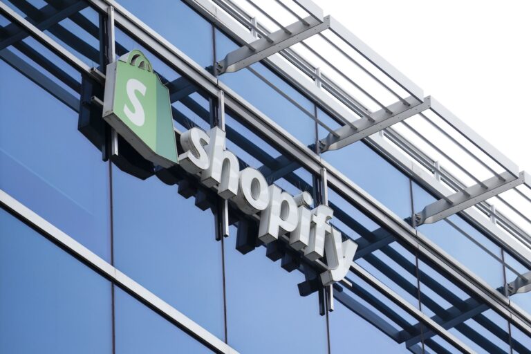 Top edge of an office building with the Shopify logo and sign visible against the glass exterior.