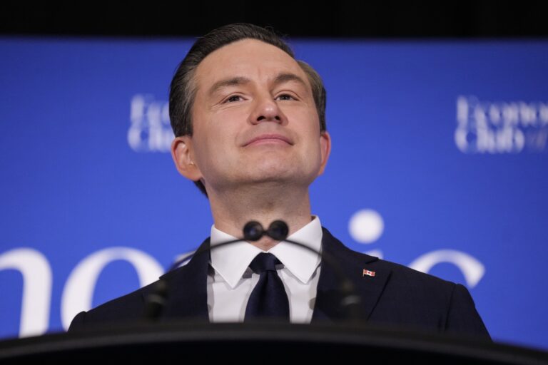 A head-and-shoulder close-up of Pierre Poilievre at a lectern, against a blue backdrop.