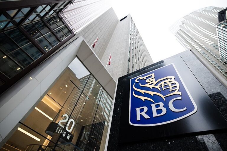 Low-angle view of an RBC logo sign in front of a tall glass-and-concrete office tower, with surrounding skyscrapers visible in the background.