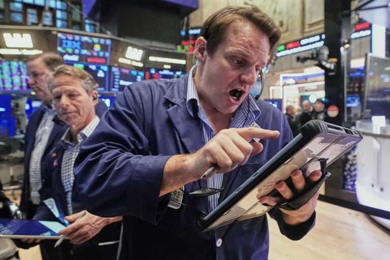 A man on the floor of the New York Stock Exchange holds a tablet