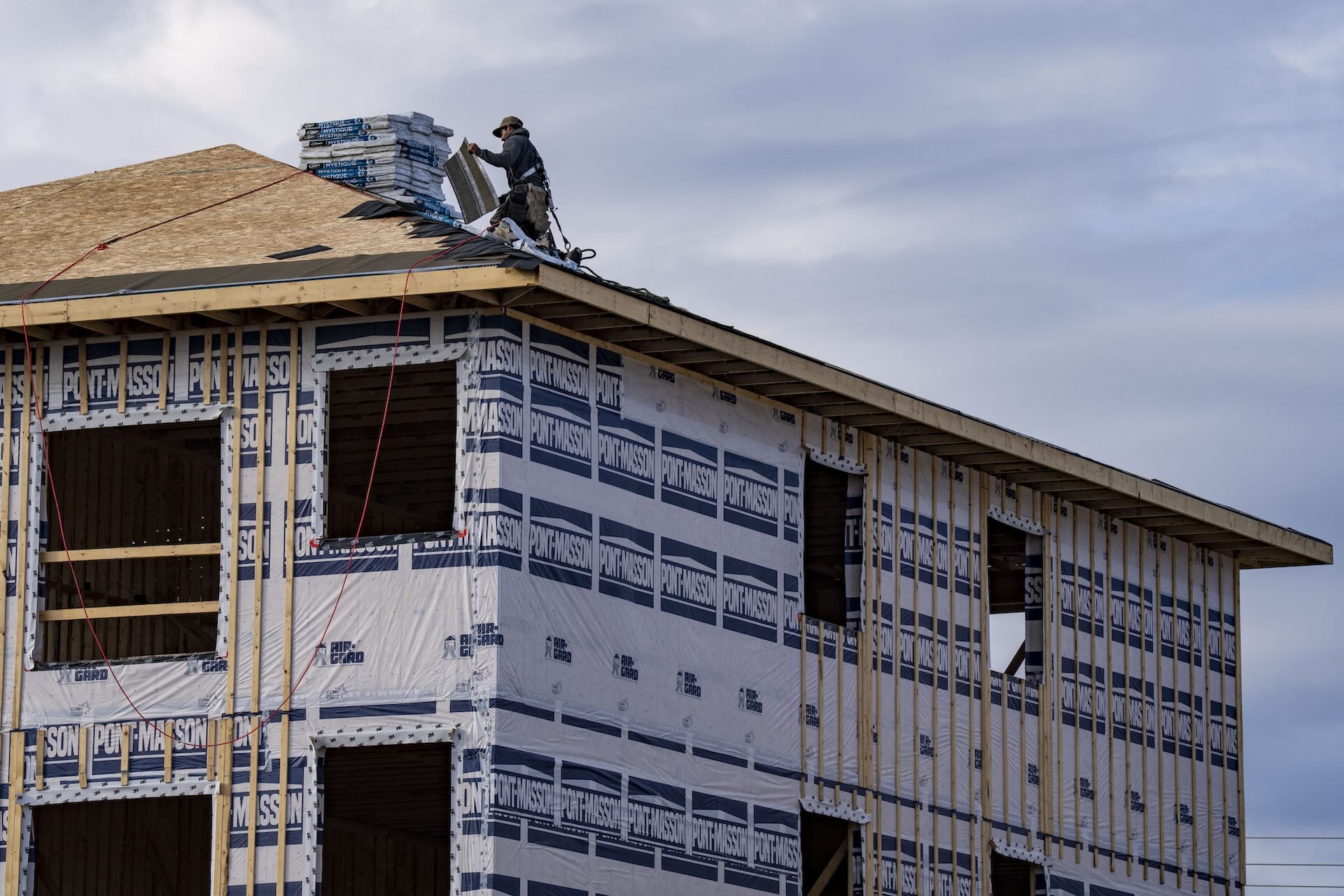 An image of a home under construction. A construction worker is seen on the roof of the house.