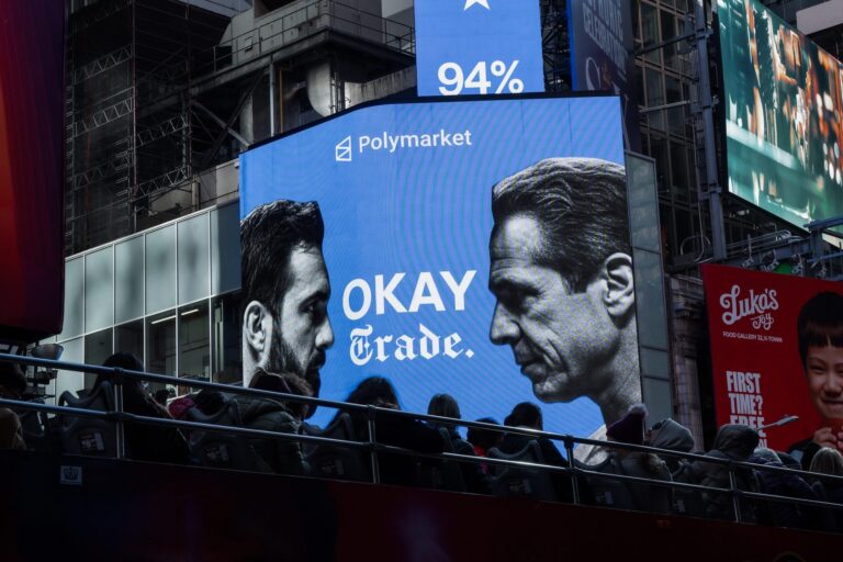 A large advertisement on the side of a building reads, "Polymarket. Okay, Trade." The shows two men facing each other.