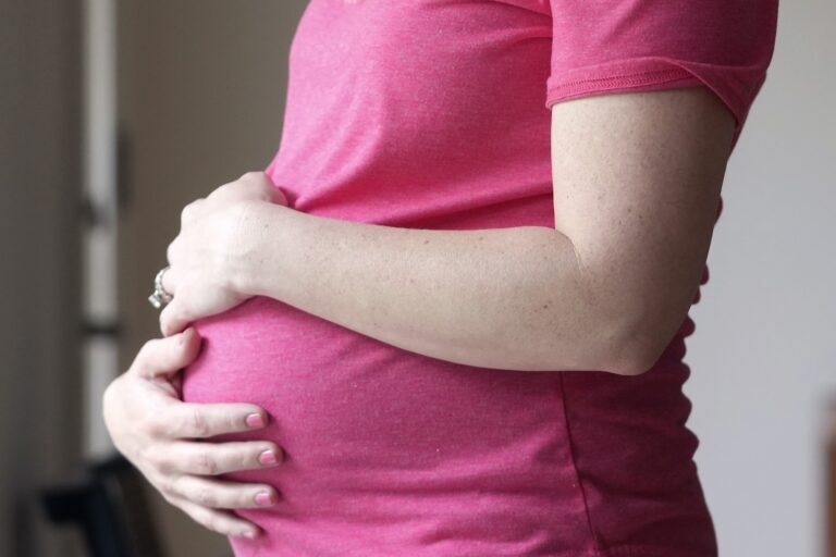 A pregnant individual wearing a pink shirt.