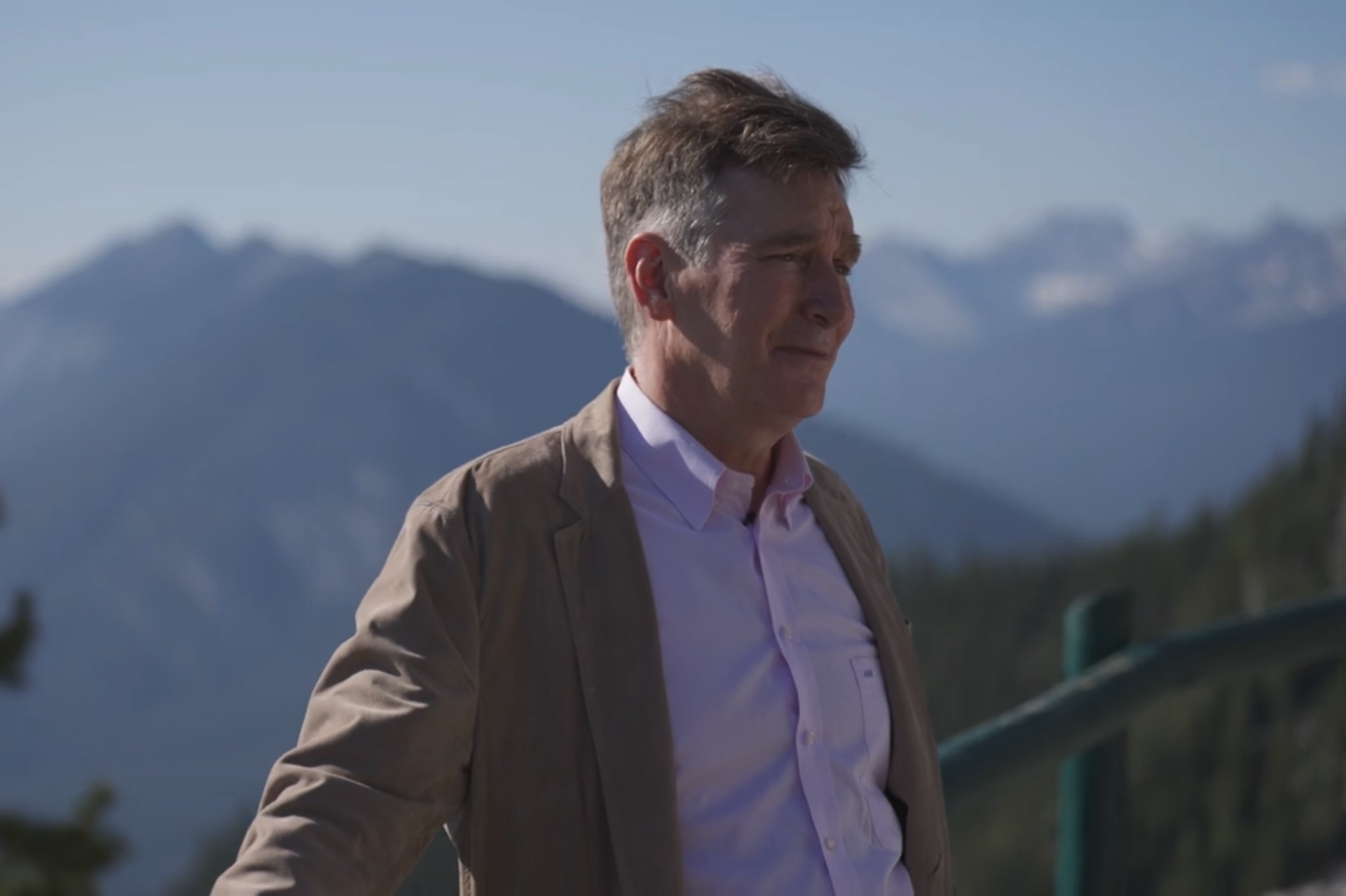 A screen-capture showing Adam Waterous against a mountain backdrop. He's wearing a tan blazer.