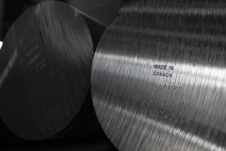 A close-up of a made-in-Canada stamp on the end of a cylindrical piece of raw aluminum.