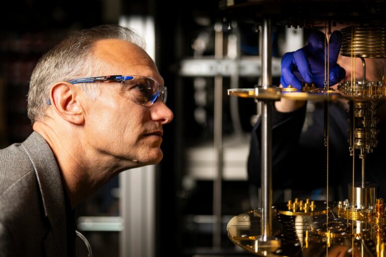 A close-up of Christopher Cassin peering into a device made up of gleaming, gold-coloured metal parts.